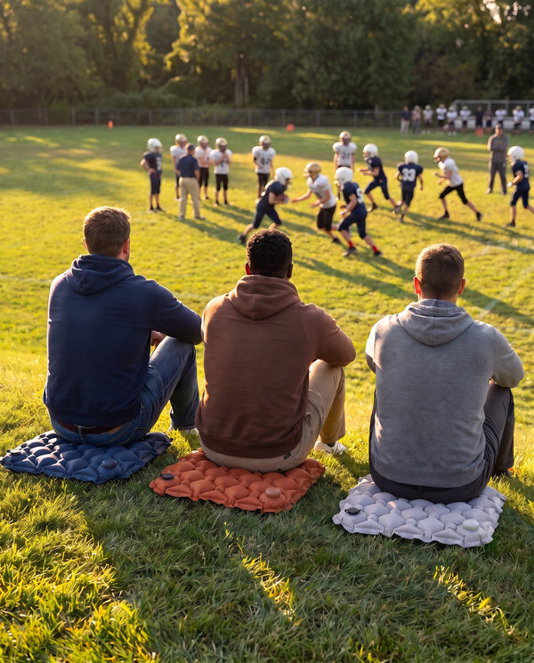 Three dads watching football practice on Crew Cushions